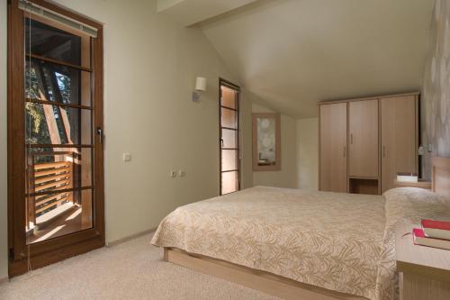 a bedroom with a bed and a large window at Effect Malina Residence Hotel in Pamporovo