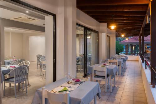 un restaurante con mesas y sillas blancas y ventanas en Matoula Beach en Ialyssos