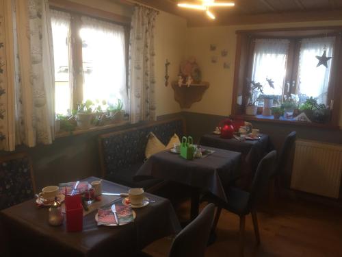 ein Esszimmer mit 2 Tischen und 2 Fenstern in der Unterkunft Gästehaus Christa in Obermaiselstein