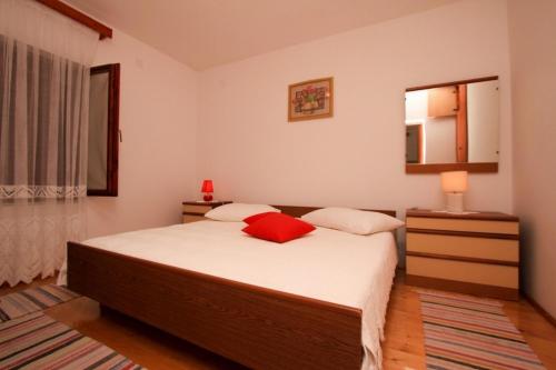 een slaapkamer met een bed met een rood kussen erop bij Apartments Brigita in Prizba