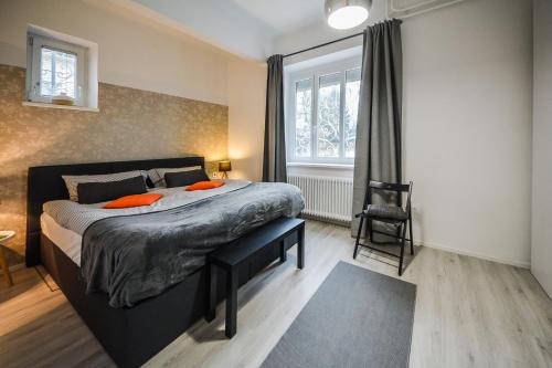 sypialnia z łóżkiem z pomarańczowymi poduszkami i oknem w obiekcie Kavon Apartments w Lublanie