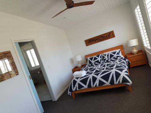 a bedroom with a bed and a ceiling fan at Zeally Bay Stay Deep Ocean in Torquay