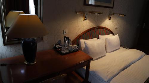 a hotel room with a bed and a lamp on a table at Hotel Super 8 in Skopje