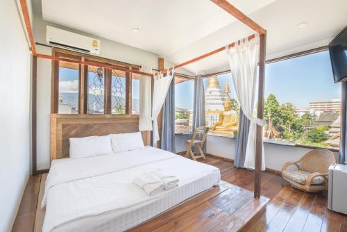 a bedroom with a bed and a large window at Sri Chiang Yeun House in Chiang Mai