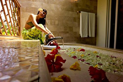 a woman in a bathroom with a tub full of leaves at Badian Island Wellness Resort in Badian