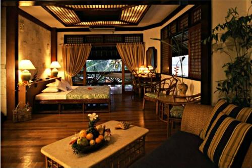 a living room with a bed and a table with fruit at Badian Island Wellness Resort in Badian