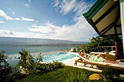 a woman laying on a chair next to a swimming pool at Badian Island Wellness Resort in Badian