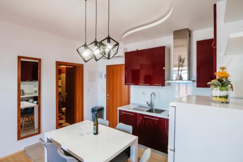 una cocina con armarios rojos y una mesa blanca en Apartments Amari, en Starigrad-Paklenica