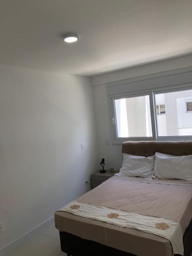 Dormitorio blanco con cama y ventana en 210 B Espelho das Aguas, en Florianópolis
