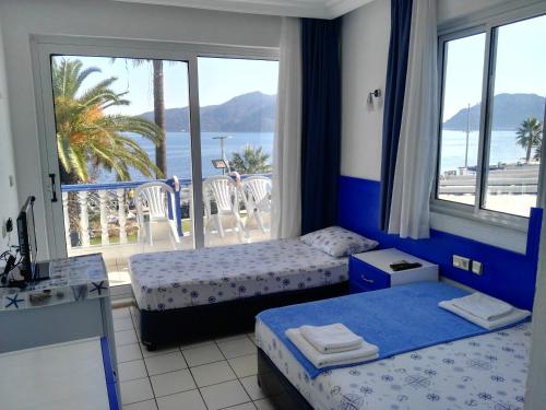 a bedroom with two beds and a balcony with the ocean at Uysal Motel Beach in Marmaris