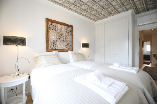 2 weiße Betten in einem weißen Schlafzimmer mit einer Decke in der Unterkunft Central Lisbon Luxury Apartment in Lissabon