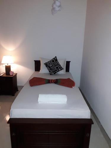 a bed with white sheets and pillows in a room at Sigiri Hibiscus Villa in Sigiriya