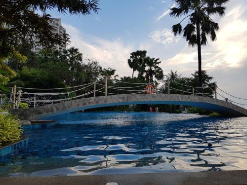 eine Brücke über einen Wasserkörper mit einem Pool in der Unterkunft Beach Front Condominium at The Palm Wongamat in Pattaya North