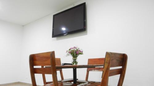 einen Tisch mit 2 Stühlen und einen TV an der Wand in der Unterkunft Hotel Saint John in Medellín