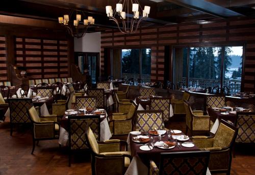 a dining room with tables and chairs and windows at The Khyber Himalayan Resort & Spa in Gulmarg
