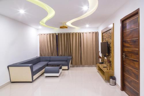 a living room with a blue couch and a tv at The Porch Inn Hotel/Service Apartments in Bengaluru