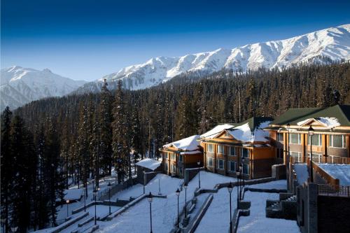 a group of buildings in the snow with mountains at The Khyber Himalayan Resort & Spa in Gulmarg