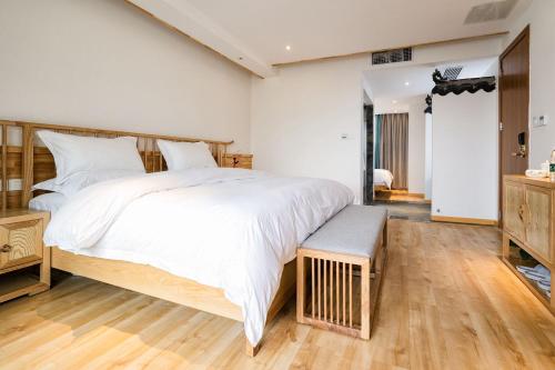 a bedroom with a large white bed and wooden floors at Zhangjiajie Su Xin Resort Near Tianmen Shan & Hehua airport-Free pick up in Zhangjiajie