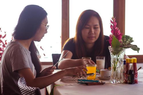 two women are sitting at a table with a table at Toba Village Inn in Tuk Tuk