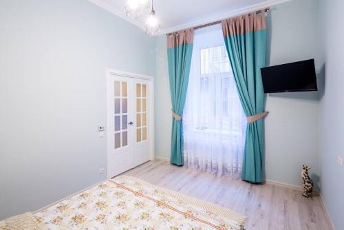 リヴィウにあるKulisha Cosy Apartmentのベッド1台、青いカーテン付きの窓が備わる客室です。