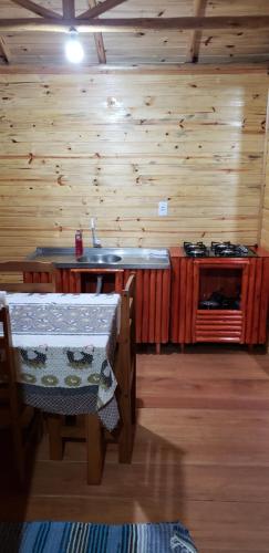 a kitchen with wooden walls and a sink and tables at Pousada do Belvedere - Sítio Ramos in Praia Grande