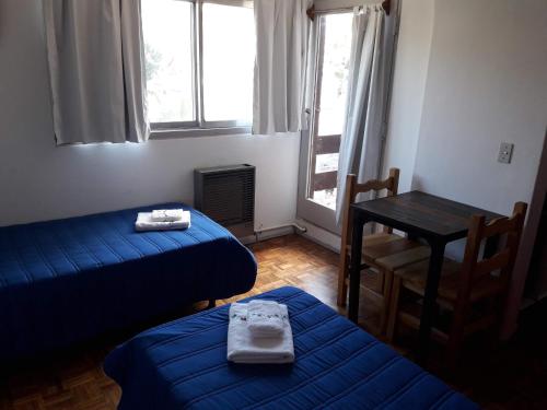 Zimmer mit 2 Betten, einem Tisch und Fenstern in der Unterkunft Deptos Irun I in San Carlos de Bariloche