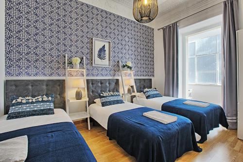 リスボンにあるAntonio Pedro Apartmentの青と白の壁紙を用いた客室内のベッド3台