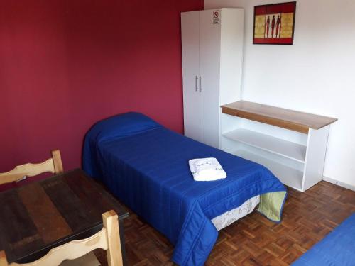ein kleines Schlafzimmer mit einem blauen Bett und einem Tisch in der Unterkunft Deptos Irun I in San Carlos de Bariloche