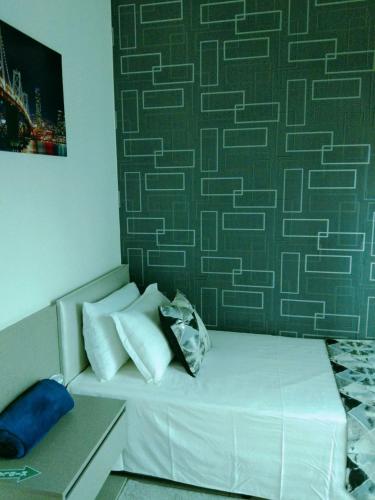 a bed with white pillows and a green wall at Evo Bangi Duplex Homestay D' Imahzzz - 3BR or 2BR in Bangi