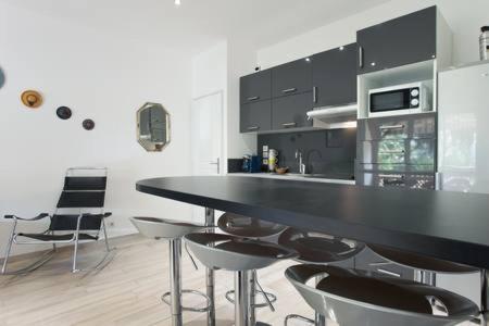 a kitchen with a black counter top and chairs at La Bigotière avec clim et jardin in Arles