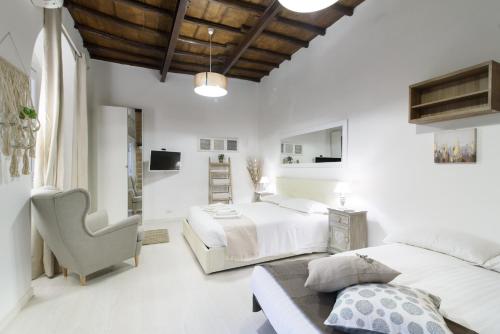 a white bedroom with two beds and a chair at White Ostilia Apartments in Rome
