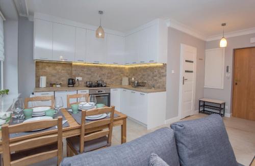 a kitchen and a living room with a table and a couch at CR Apartament Ścisłe Centrum Aleja Bluesa in Białystok