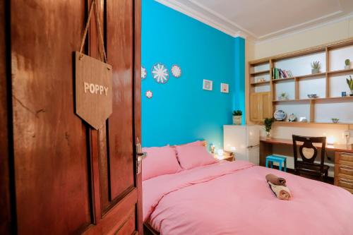 ein Schlafzimmer mit einem rosa Bett und einer blauen Wand in der Unterkunft Kalon Homestay, Hai Bà Trưng, HN in Hanoi