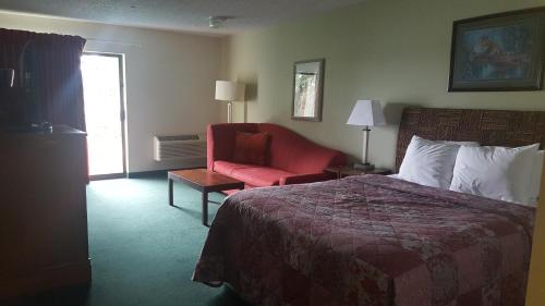 Pokój hotelowy z łóżkiem i czerwonym krzesłem w obiekcie Oyster Bay Inn & Suites w mieście Bremerton