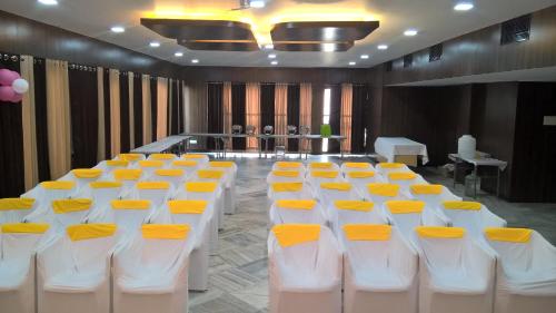 a conference room with white and yellow tables and chairs at Hotel Supreme in Madurai