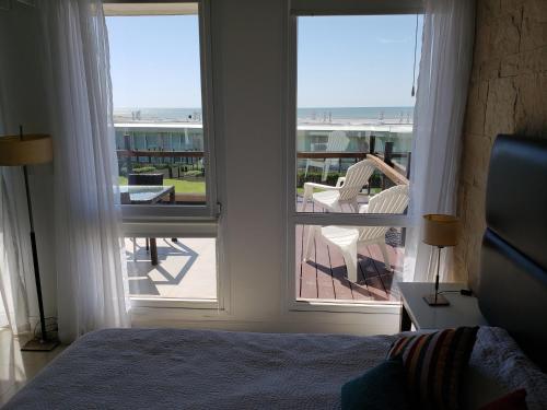 1 dormitorio con cama y vistas a un balcón en Linda Bay Beach & Resort Spa en Mar de las Pampas