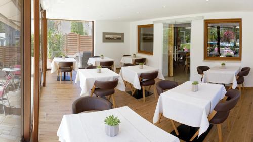 a restaurant with white tables and chairs and windows at Pension Sattlerenglhof in Laces