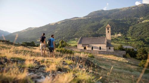 two men standing on a hill looking at an old church at Pension Sattlerenglhof in Laces