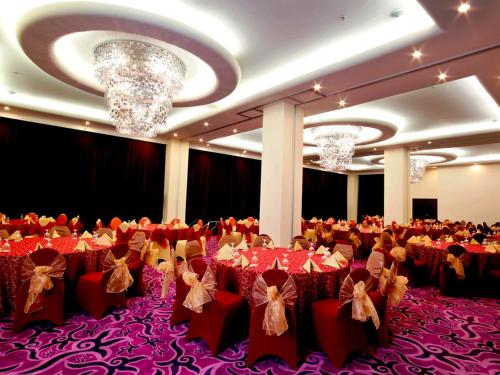 a banquet hall with red tables and chairs and chandeliers at Swiss-Belhotel Ambon in Ambon