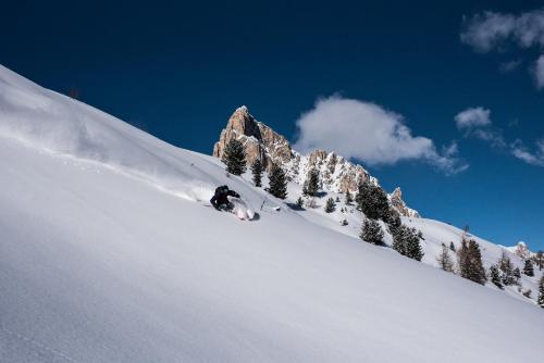 a person is skiing down a snow covered mountain at FIORI Dolomites Experience Hotel in San Vito di Cadore