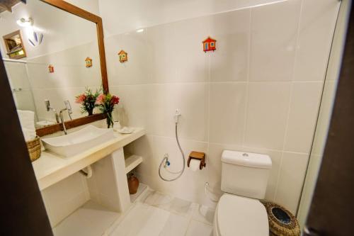 a bathroom with a toilet and a sink and a mirror at Pousada Campestre in Trancoso
