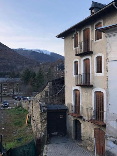 an old building with a door and a balcony at Casa Serraller in Esterri d'Àneu