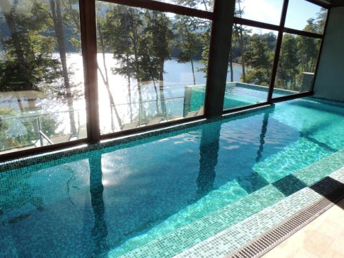 uma piscina com vista para a água através de uma janela em Departamento con vista al lago y piscina climatizada em Villa La Angostura