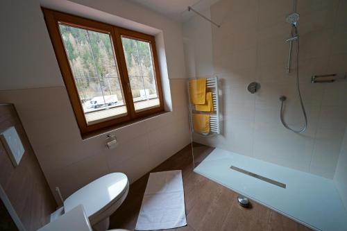 a bathroom with a toilet and a shower with a window at Quellenhof in Oberlängenfeld