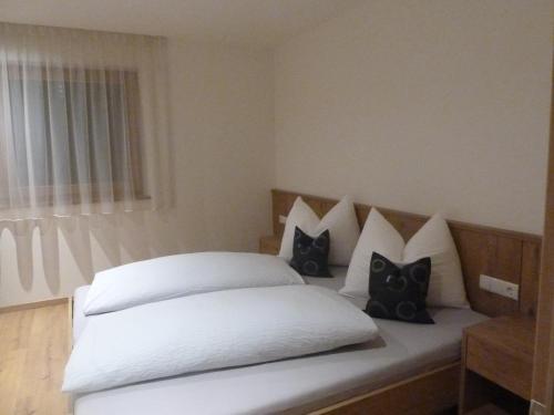 a bed with black and white pillows on it at Chalet Morin in San Martino in Badia
