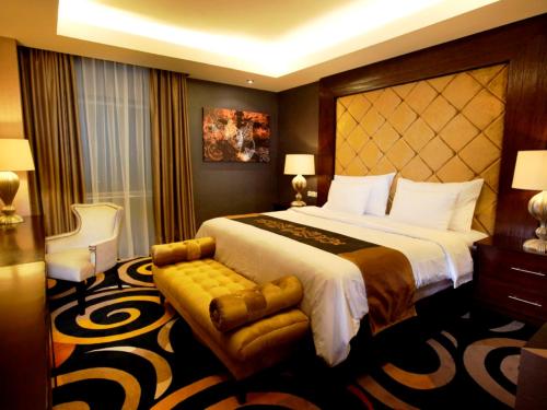 a hotel room with a large bed and a chair at Swiss-Belhotel Ambon in Ambon