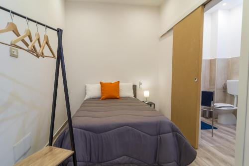 - une chambre avec un lit et un oreiller orange dans l'établissement Giù al Centro, à Naples