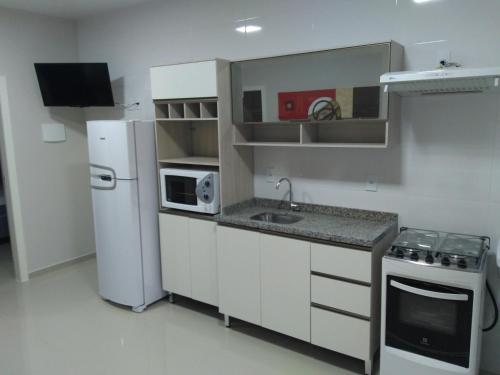 cocina con nevera blanca y microondas en Residencial Mariano 2 - Vista para praia e Mar, en Florianópolis