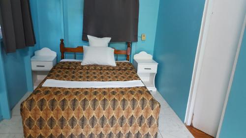 a bedroom with a bed with blue walls at Chez Ophelia Cottage Apartments in Roseau