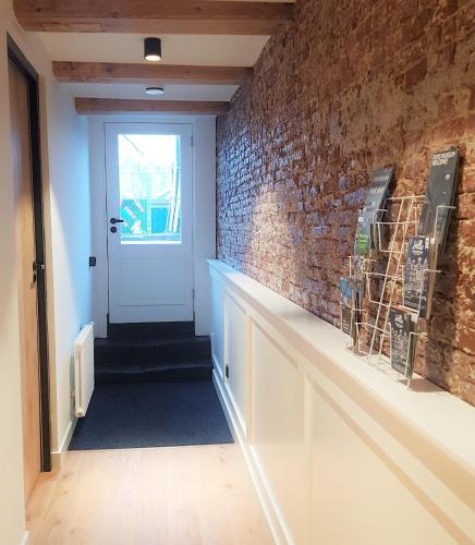 a hallway with a brick wall and a white door at 23 SouS in Amsterdam